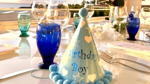 Une table dressée pour une fête d’anniversaire, avec un chapeau de fête bleu et un menu.