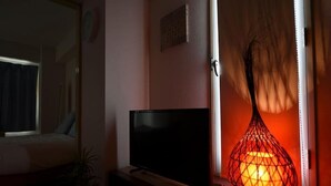 A room with a TV on a stand, a plant, and a decorative lamp. - Kentaku29 BLD. 72 (Sapporo)