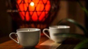 Two white ceramic cups on a wooden surface with a warm, glowing light fixture in the background. - Kentaku29 BLD. 72 (Sapporo)