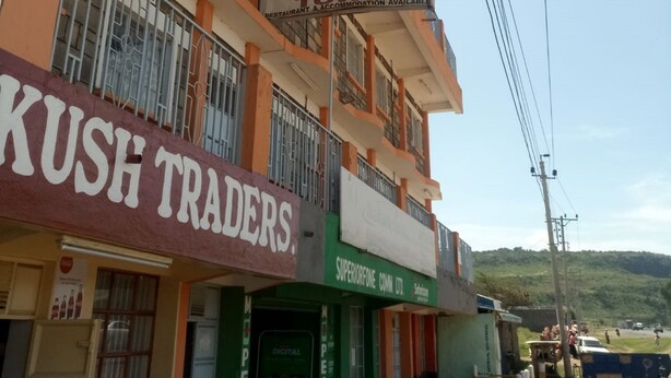 A multi-story building with commercial establishments on the ground floor, including a restaurant and a trading business. - Yumwema Guest House (Nakuru)