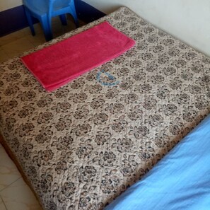 Una cama con una colcha estampada y una toalla roja.