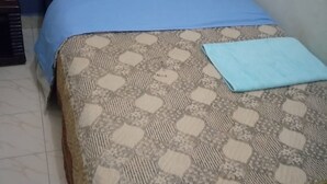 A bed with a patterned bedspread and a blue pillow. - Yumwema Guest House (Nakuru)
