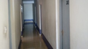 A narrow, well-lit hallway with a tiled floor and walls painted in a light color. - Yumwema Guest House (Nakuru)
