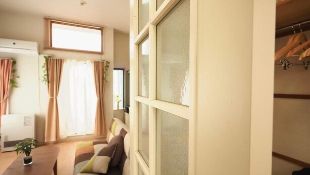 A cozy living room with a sofa, a coffee table, and a window with curtains. - Opus 802 (Sapporo)