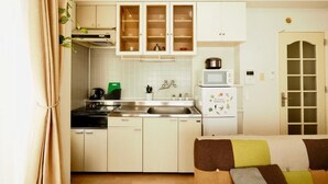 A compact kitchen with white cabinets, a microwave, a sink, and a refrigerator. - Opus 802 (Sapporo)