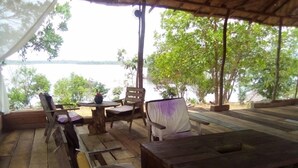An outdoor wooden deck with a table and chairs, overlooking a body of water.