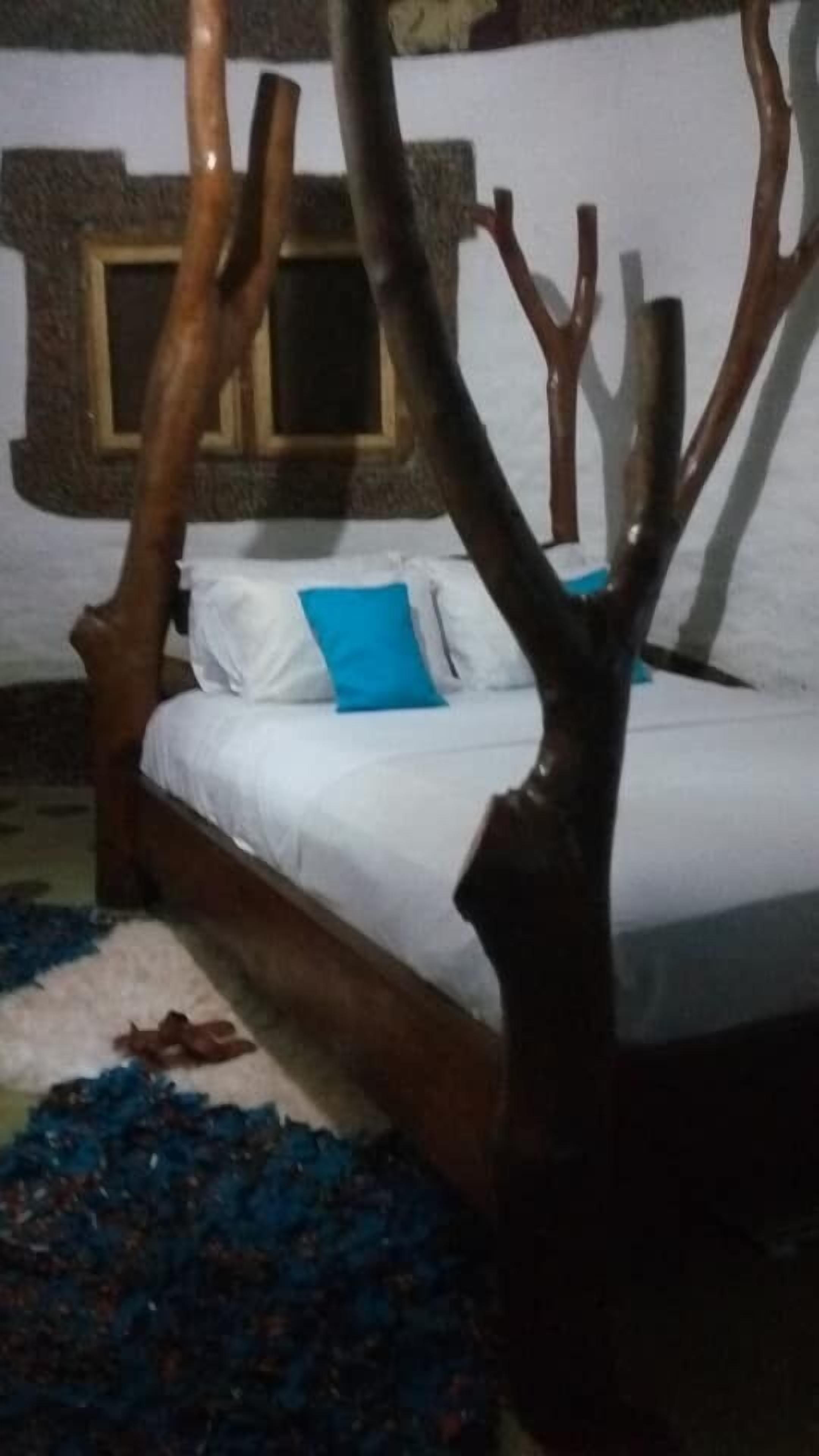 A bed with a wooden headboard, white bedding, and blue pillows.