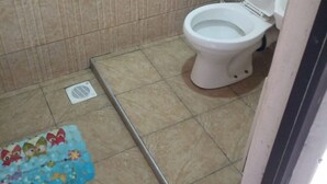 A small bathroom with a toilet, tiled walls, and a vent on the floor. - Venus lodge Kikopeye (Gilgil)