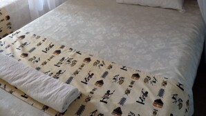 A bed with a white bedspread and a patterned blanket, a white pillow, and sheer curtains. - Venus lodge Kikopeye (Gilgil)