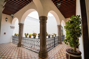 An architectural corridor with arches, columns, and potted plants. - Hotel Señorial (Querétaro)
