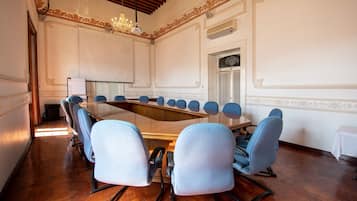 Un salón de conferencias con una mesa larga, sillas azules y una lámpara de araña.