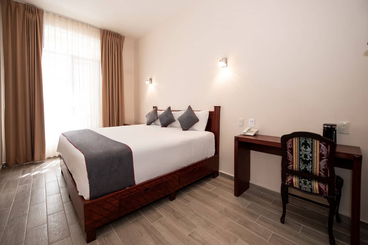 Et hotelværelse med en seng, et skrivebord og en stol.