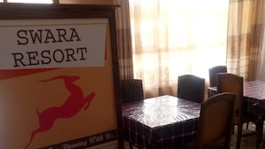 A dining area with a sign reading "SWARA RESORT" and a thank you message. Tables are covered with checkered tablecloths, and chairs are arranged around them. - Swala Resort (Gilgil)