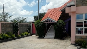 A building with a red-tiled roof, a staircase leading to a door, and a concrete ground. - Swala Resort (Gilgil)