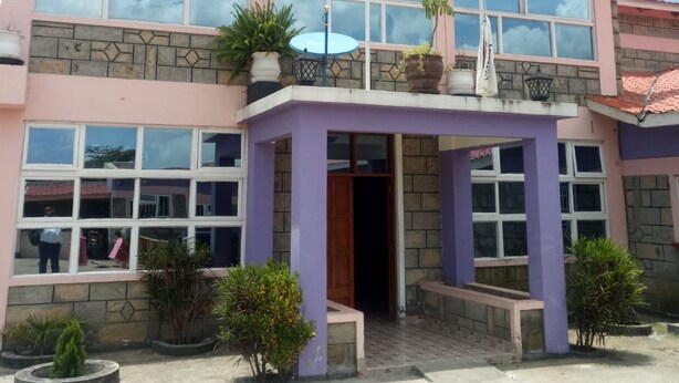 A two-story building with a sign reading "SWARA" at the top. There are multiple windows on both floors, and the building has a pink and grey color scheme. - Swala Resort (Gilgil)