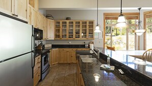 A kitchen with wooden cabinets, a stainless steel sink, granite countertops, and pendant lighting. - Beautiful mountain views from this immaculate 3 bedroom ski and summer condo (Whitefish)