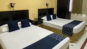 A hotel room with two beds, each with a black headboard, white linens, and blue pillows. There is a wall-mounted TV and a small table with a phone. - Hotel Impala de Tampico (Tampico)
