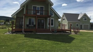 A two-story house with a porch, a garage, and a well-maintained lawn. - Beautiful Bear Lake House, with big grassy yard, 4 mins to North Beach. (St Charles)