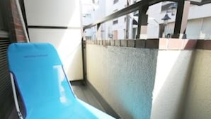 A blue medical examination bed in a narrow corridor with a white wall and a door on the left. - Lions Mansion Dogenzaka 207 (Tokyo)