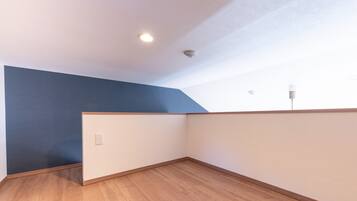 A corner room with a sloped ceiling, wooden flooring, and a blue accent wall.