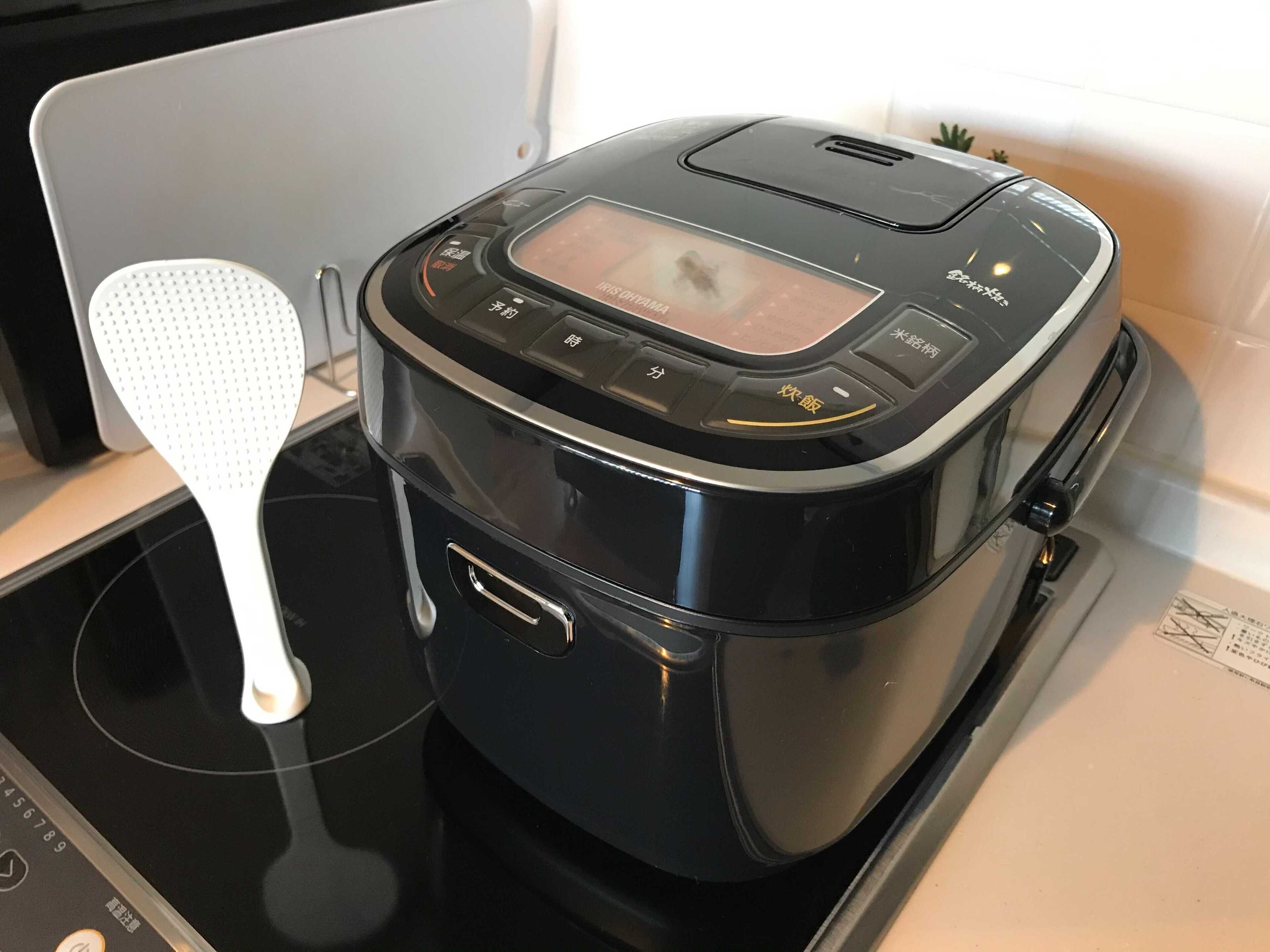 A black electric kettle with a digital display and multiple buttons on a black stovetop.