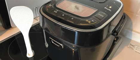 A black electric kettle with a digital display and multiple buttons on a black stovetop.