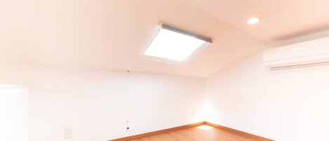 Una habitación con techo inclinado, iluminación empotrada y tragaluz.