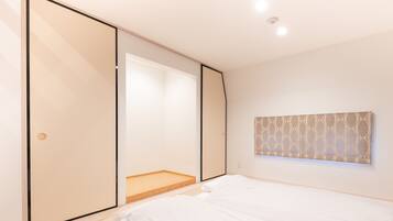 Un dormitorio con un amplio ventanal corredera, una cama, una pequeña plataforma de madera y un adorno mural con estampado.