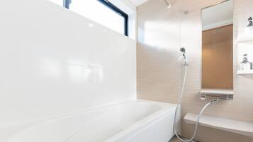 Un baño moderno con bañera, ducha y un espejo grande.