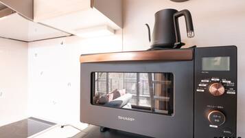 Une cuisine équipée d’un four à micro-ondes, d’une machine à café et d’un panneau de commande numérique.