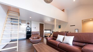 Una sala de estar moderna con un sofá de cuero marrón, una mesa de centro de madera y una escalera de madera.