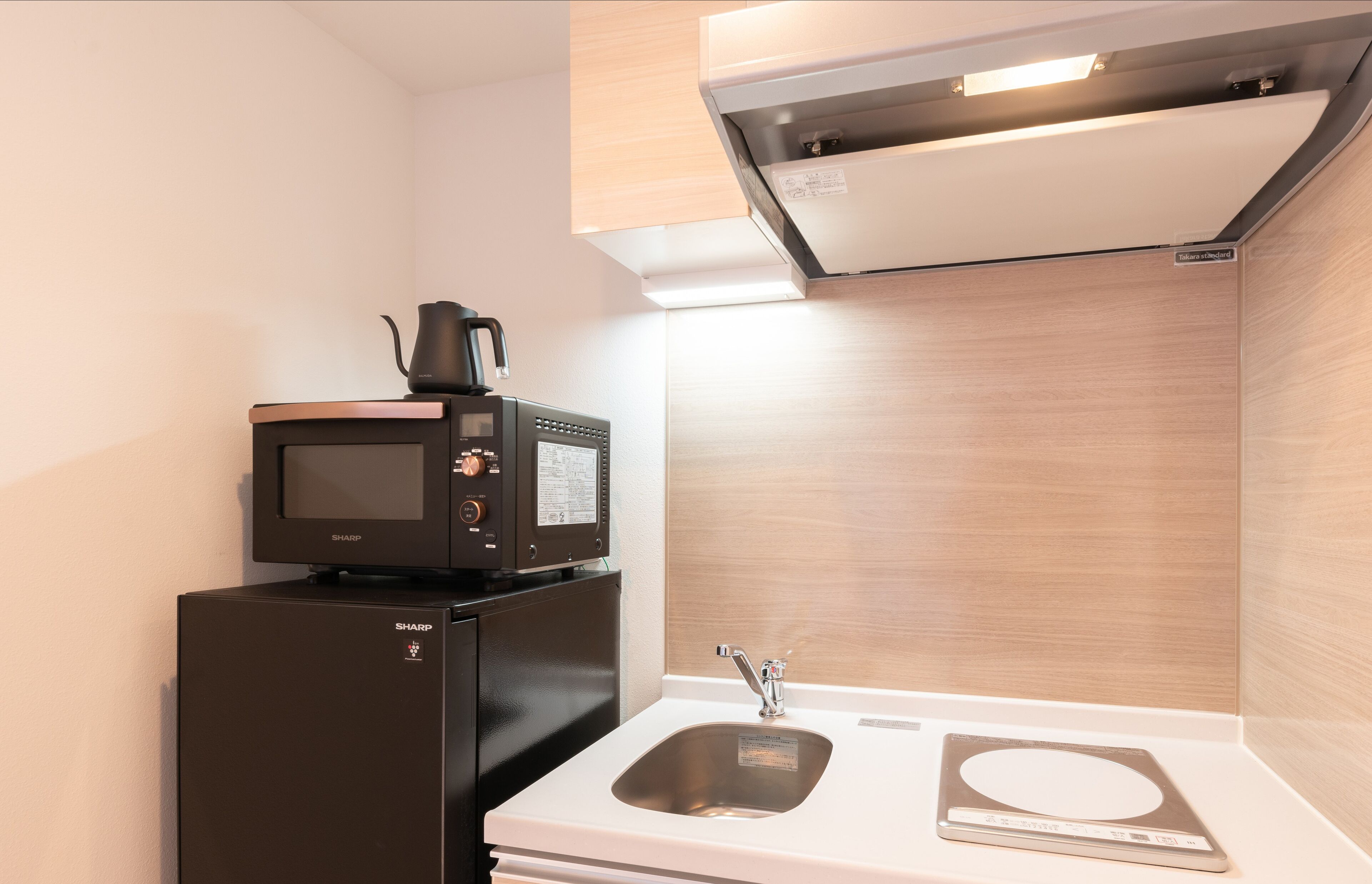 A compact kitchen with a microwave, a coffee maker, a sink, and a built-in scale.