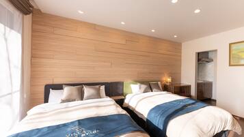 Habitación de hotel con dos camas, cabecera de madera, mesita de noche con lámpara y ventana con cortinas.