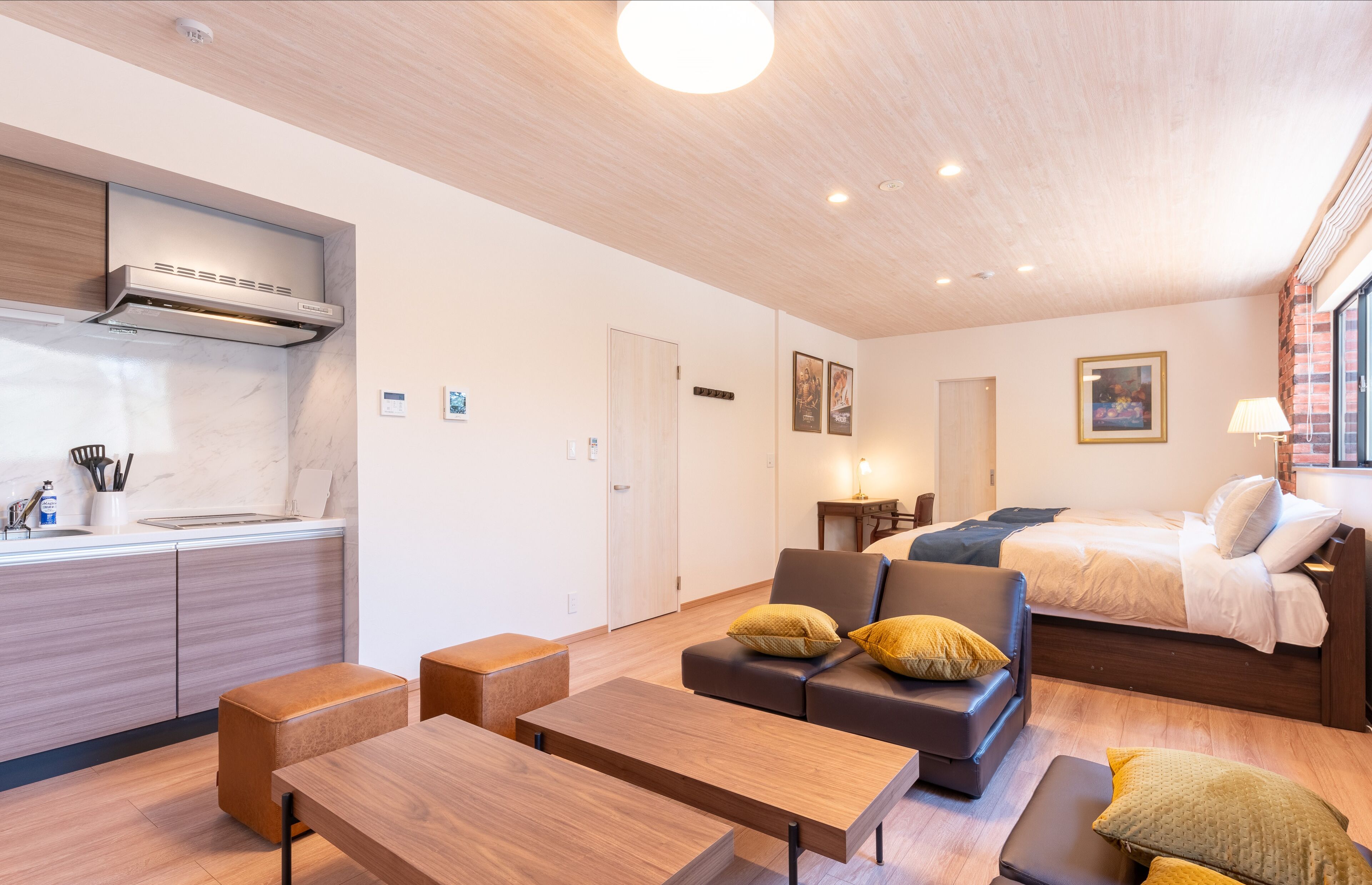 Ein modernes Hotelzimmer mit Küchenzeile, einer Couch, einem Bett und einem Essbereich.