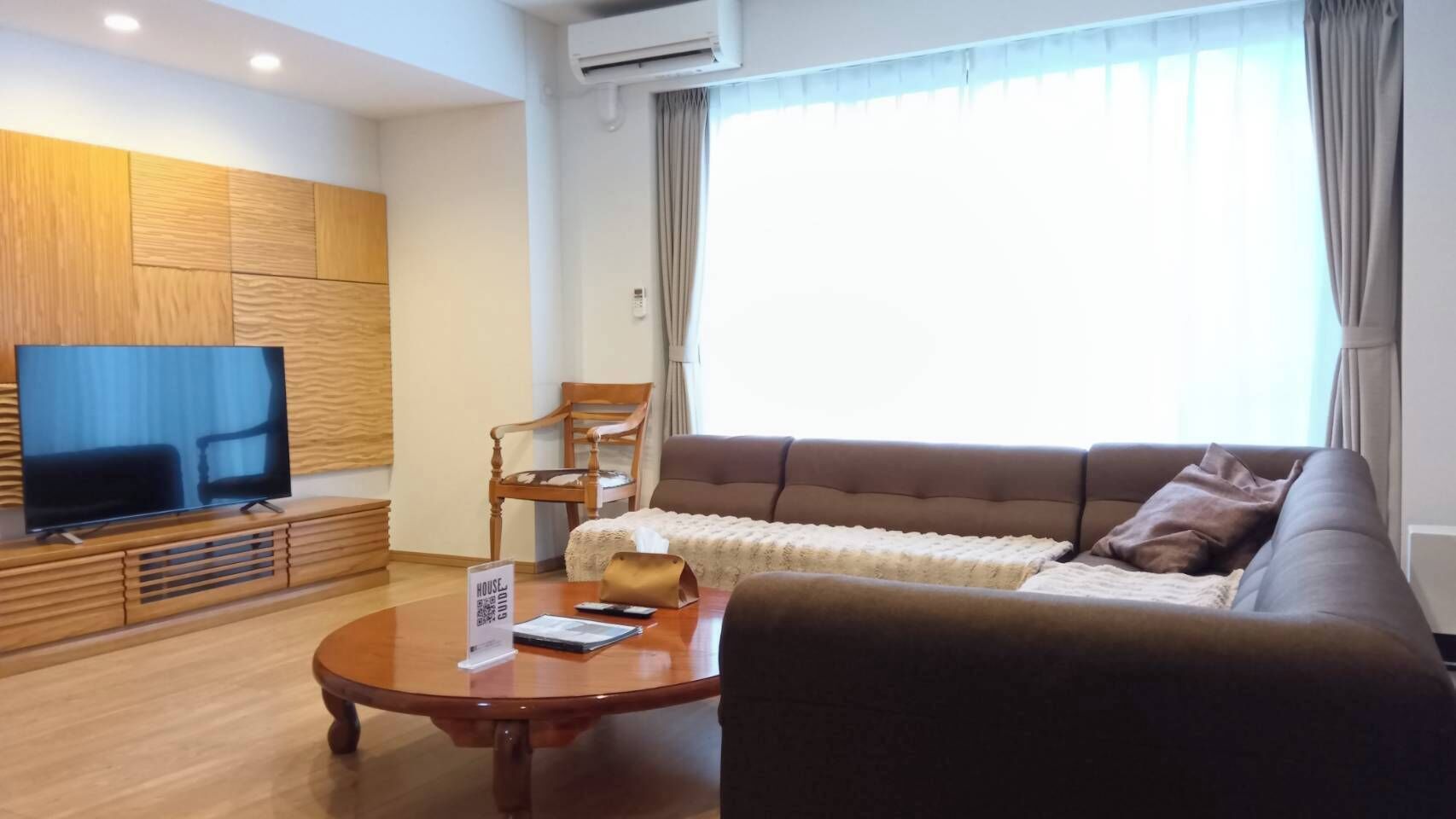 A modern living room with a flat-screen TV, a sofa, a coffee table, and a wooden cabinet.