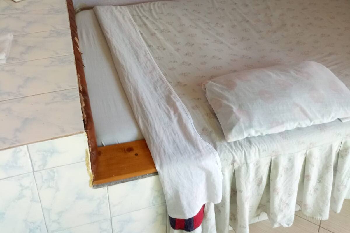 A bedroom with a bed, a wooden headboard, a bedside table, and a book on the floor.
