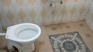 A bathroom with a toilet, a sink, and patterned tiles. - Smartie Guest House (Nakuru)