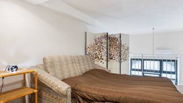 Una camera da letto con un letto, una poltrona con motivi decorativi, uno scaffale in legno e un pannello decorativo a parete.
