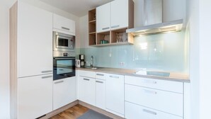 A modern kitchen with white cabinets, a built-in oven, a microwave, and a coffee maker.