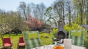 Een buitenterras met een tafel voor twee personen, omringd door groene stoelen.