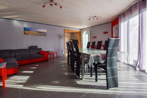 Una sala de estar moderna con sofá, mesa de comedor, sillas y vistas a través de un arco.