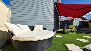 A round wicker bed with white cushions, a red canopy, and artificial grass in a courtyard. - Poolside Escape by Arcachon (La Teste-de-Buch)