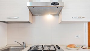 A modern kitchen with a stainless steel range hood, a double sink, and a built-in oven.