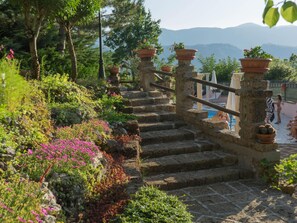 A stone staircase with terracotta pots on the balusters, surrounded by lush greenery and flowers. - Villa in Tagliacozzo With Pool and Nature (Tagliacozzo)