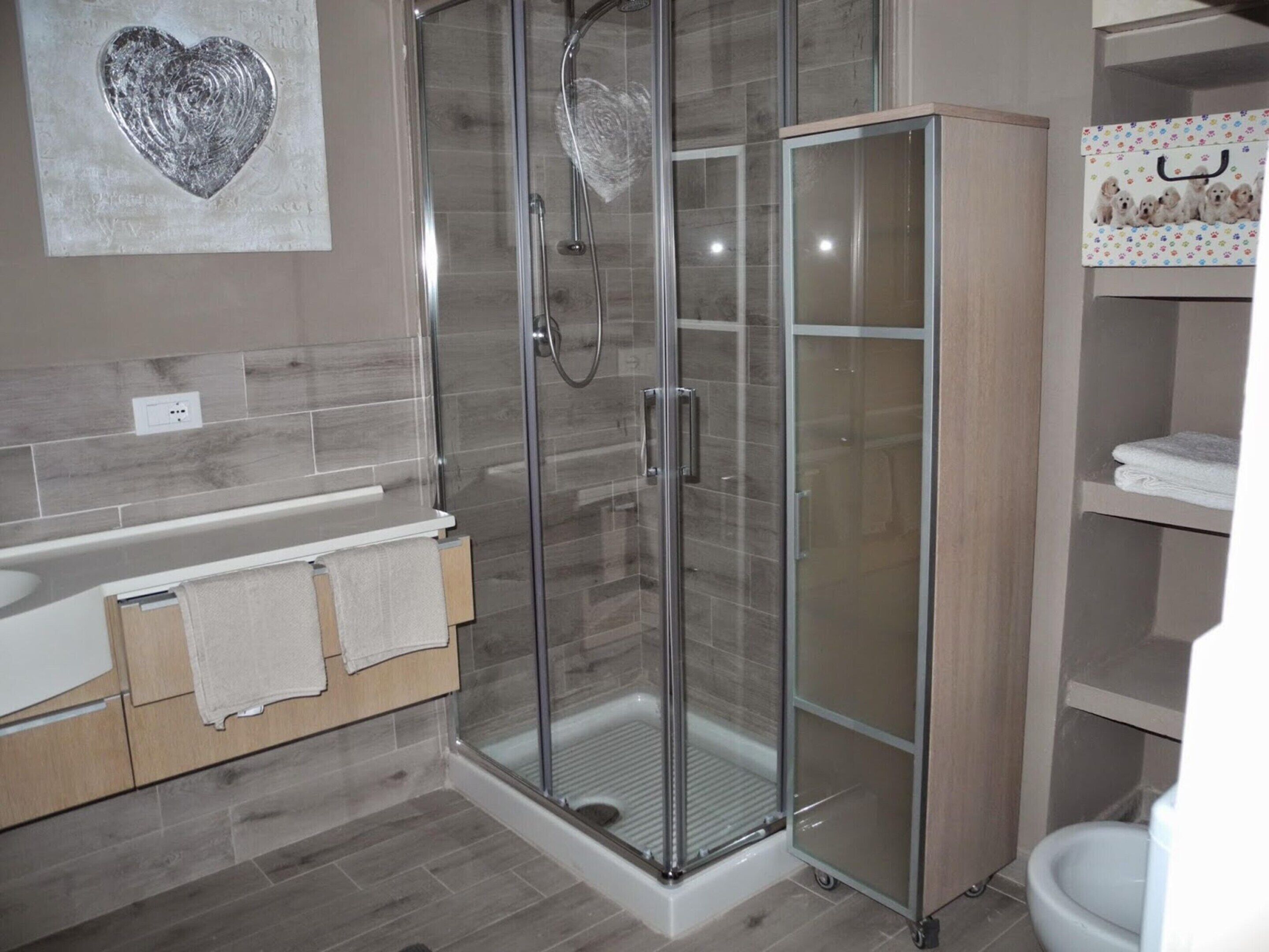 A modern bathroom with a glass-enclosed shower, a white sink, and a toilet.