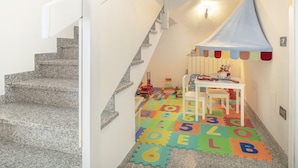 Una escala amb una zona de jocs a la base, que inclou un estenedill de joc amb les lletres de l'alphabet i una taula petita amb joguines.