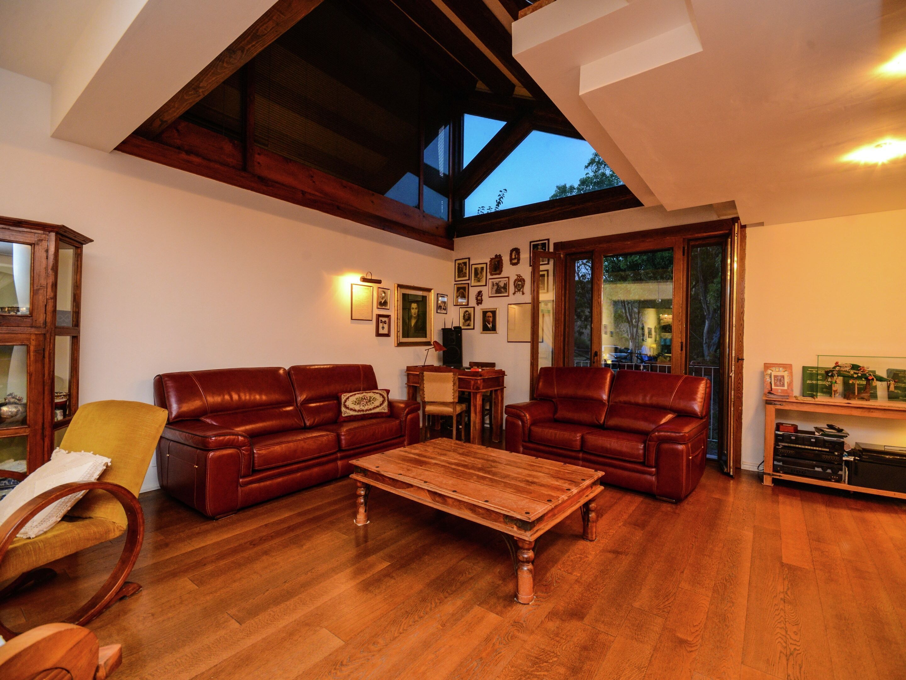 Un salon spacieux doté d’un plancher en bois, de deux canapés en cuir, d’une table basse en bois et d’une grande fenêtre donnant sur l’extérieur.