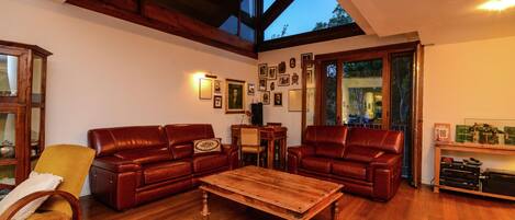 Un salon spacieux doté d’un plancher en bois, de deux canapés en cuir, d’une table basse en bois et d’une grande fenêtre donnant sur l’extérieur.