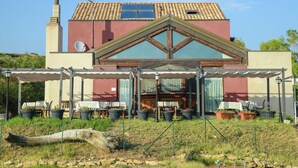 A house with a red facade, a pitched roof, and a covered patio area with outdoor seating. - Holiday Home in Cropani Marina With Pool (Badolato)