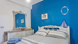 A bedroom with a bed, a dresser, a mirror, and a blue wall. - Cosy Holiday Home in Sanremo With Sea Beach Nearby (Alcamo)